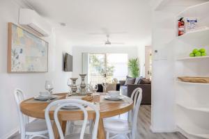 a dining room and living room with a table and chairs at Aquamarine - modern & bright Huskisson townhouse in Huskisson