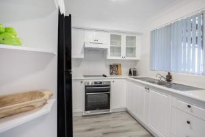 a kitchen with white cabinets and a sink at Aquamarine - modern & bright Huskisson townhouse in Huskisson