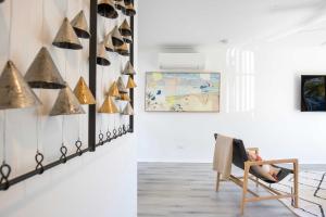 a person sitting in a chair in a room with a painting at Aquamarine - modern & bright Huskisson townhouse in Huskisson +23 photos