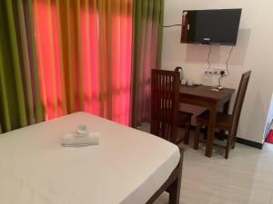 a room with a bed and a table and a television at Aluthwewa Gate in Angunakolapelessa