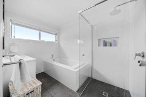 a white bathroom with a shower and a sink at Bowen View - pet-friendly home near Hyams Beach in Hyams Beach