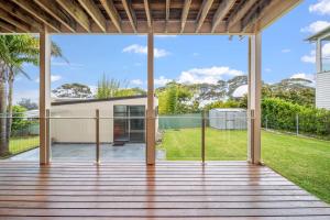 an open deck with a view of a house at Footprints at Hyams Beach - 4BR home w. games room in Hyams Beach