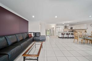 a living room with a couch and a table at Footprints at Hyams Beach - 4BR home w. games room in Hyams Beach +14 photos