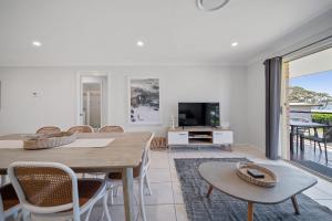a dining room with a table and chairs and a television at Days By The Bay - 3BR house with ocean views in Hyams Beach