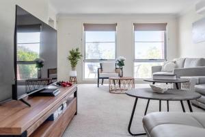 a living room with a couch and a tv at Amalena by the sea - Vincentia 5BR home with pool in Vincentia