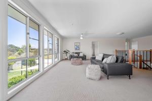 a living room with a couch and chairs and windows at Amalena by the sea - Vincentia 5BR home with pool in Vincentia