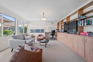 a living room with a couch and a tv at Amalena by the sea - Vincentia 5BR home with pool in Vincentia
