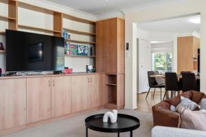 a living room with a tv and a couch and a table at Amalena by the sea - Vincentia 5BR home with pool in Vincentia