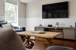a living room with a table and a flat screen tv at Karinya Jervis Bay - 4BR home & optional studio in Vincentia +18 photos