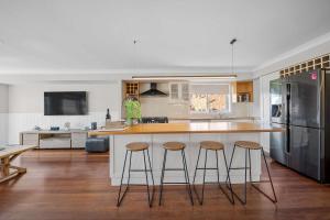 a kitchen with three bar stools at a kitchen counter at Karinya Jervis Bay - 4BR home & optional studio in Vincentia