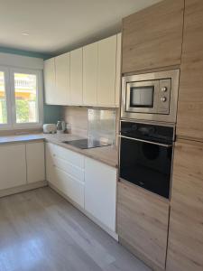 a kitchen with white cabinets and a black microwave at Casa Flores in El Campello +14 photos