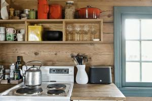 a kitchen with a stove and shelves with glasses at Traditional Log Cabin At Vierli in Rauland