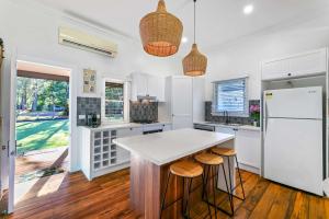 a kitchen with a white counter and stools at The Shack - Myola in Myola