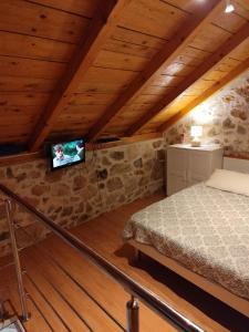 a bedroom with a bed and a tv on a stone wall at Krka Waterfalls Stonehouse Roko in Lozovac