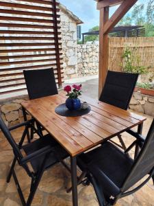 a wooden table with two chairs and a vase with flowers at Krka Waterfalls Stonehouse Roko in Lozovac