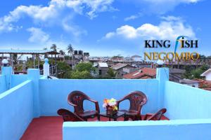 een balkon met 2 stoelen en een tafel met bloemen bij King Fish Guest House in Negombo