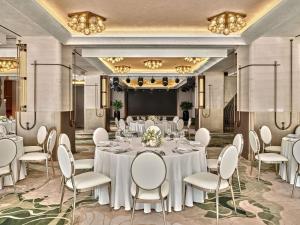 a banquet room with white tables and chairs and a stage at Swissotel Tashkent in Tashkent +122 photos