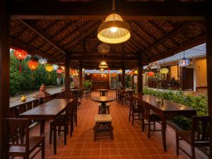 a restaurant with wooden tables and chairs and lights at Villa Khili Phousi in Luang Prabang