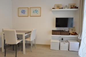 - une salle à manger avec une table, des chaises et une télévision dans l'établissement Casa di Alessandra, à Rome