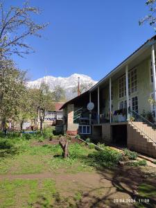 a large building with mountains in the background at Alpinist Homestay in Arslanbob