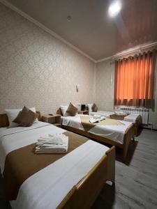 a room with three beds and a window at Polvon Ota Hotel in Khiva +10 photos