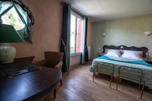 a bedroom with a bed and a table and a window at Beauséjour in Calvinet