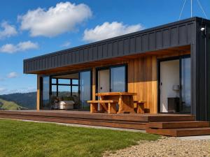 a small house with a table on a deck at Ocean Waters in Mahia