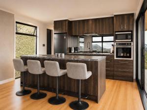 a kitchen with a large island with bar stools at Ocean Waters in Mahia +12 photos