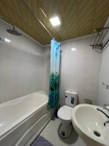 a bathroom with a tub and a toilet and a sink at Polvon Ota Hotel in Khiva