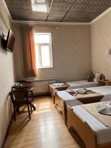 a room with four beds and a table and a window at Polvon Ota Hotel in Khiva