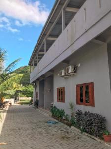 a white building with red doors and windows at Anorawi Surf accommodation in Maluk