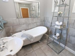 a bathroom with a tub and a sink and a mirror at Blacksmiths Cottage in Alnwick +42 photos