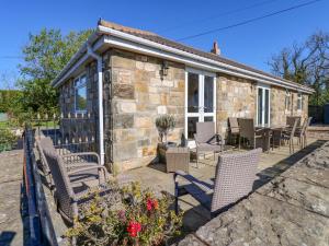 a stone house with chairs and a patio at Blacksmiths Cottage in Alnwick