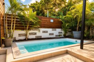 a swimming pool in a backyard with palm trees at Eau clair de lune - Vincendo in Saint-Joseph