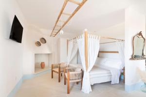 a white bedroom with a bed and a chair at Masseria Rauccio in Torre dell'Orso