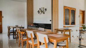 a dining room with a wooden table and chairs at Tentram Guest House in Waikabubak