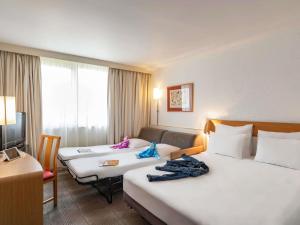 a hotel room with two beds and a television at Hotel Novotel Evry Courcouronnes in Courcouronnes
