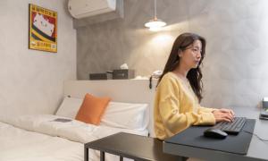 a woman sitting at a desk with a computer at Uiwang Nine Hotel in Uiwang