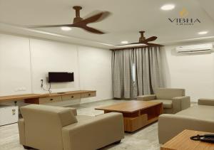 a living room with a ceiling fan and a table and chairs at Hotel Vibha Grand in Karīmnagar