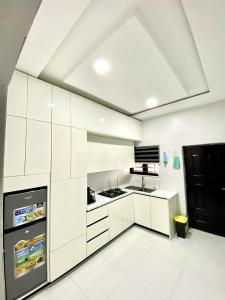 a white kitchen with white cabinets and a ceiling at Aulein Apartments in Abuja