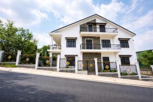 a white house with black windows and a fence at LaLa Villa Đà Lạt in Da Lat