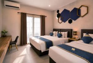 a hotel room with two beds and a desk at Casananta Seminyak in Seminyak