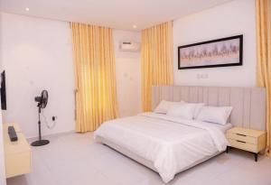 a bedroom with a white bed and yellow curtains at Aulein Apartments in Abuja