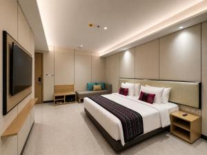 a hotel room with a bed and a television at Prime Plaza Hotel Mataram in Mataram