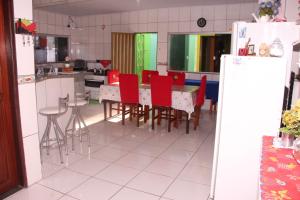 a kitchen with a dining table and red chairs at Pousada Familiar Encanto da Chapada in Carolina