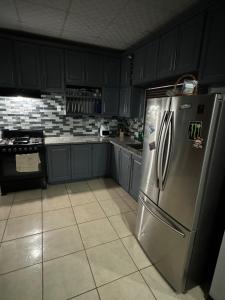 a kitchen with black cabinets and a stainless steel refrigerator at Casa No6 Ascot in Carapo