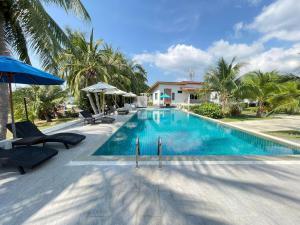 a pool with chairs and umbrellas next to a house at Breeze Bay Villas Koh Phangan in Wok Tum
