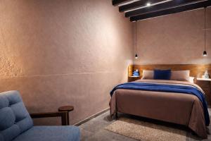 a bedroom with a bed and a blue chair at Casa UMA in San Miguel de Allende