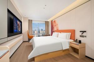 a hotel room with a white bed and a tv at 枫渡酒店上海陆家嘴世纪大道地铁站店 in Shanghai