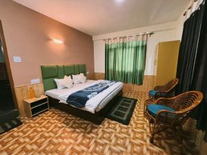 a bedroom with a bed with a green headboard and chairs at Non Stop Cafe Hostel & Stay in Manāli